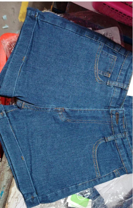 blue denim shorts with front pockets and belt loops folded on a cluttered surface