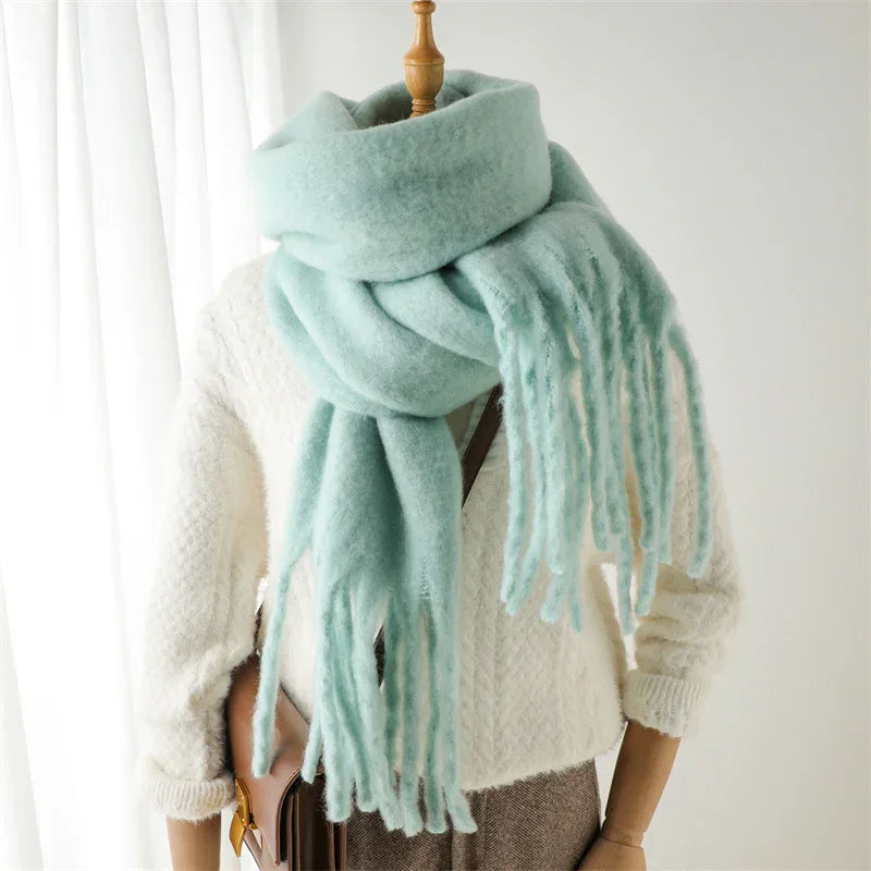 Soft light blue oversized wool scarf with fringes styled on mannequin wearing white knit sweater