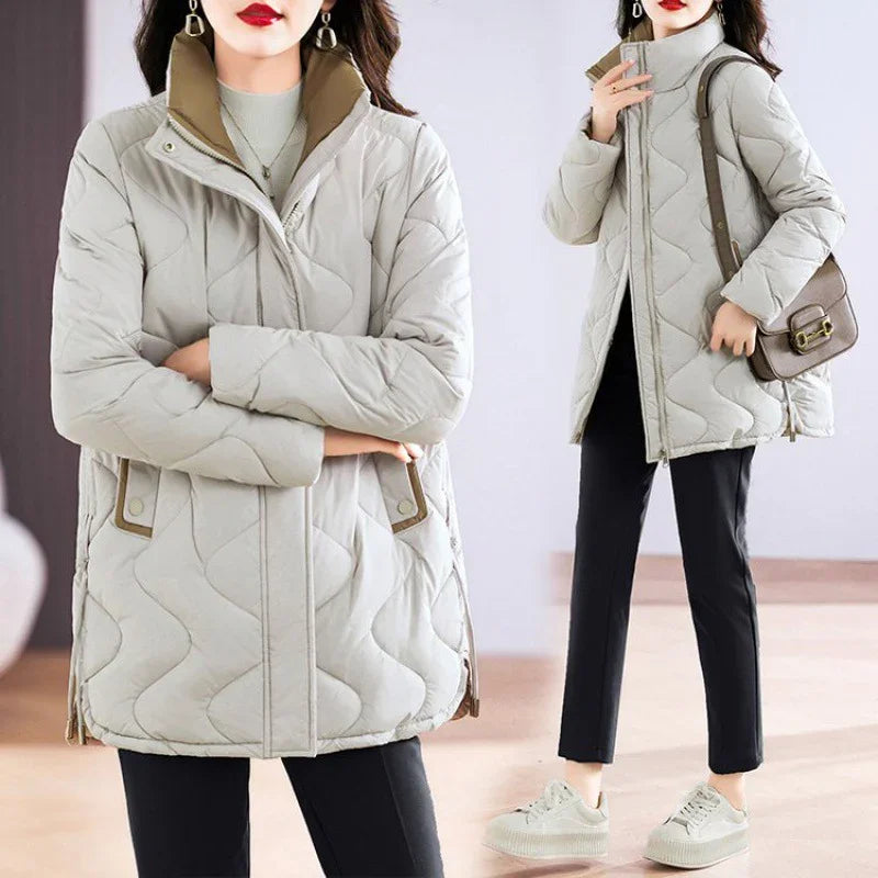 Woman wearing beige quilted winter jacket with high collar, black pants, beige sneakers, and brown shoulder bag