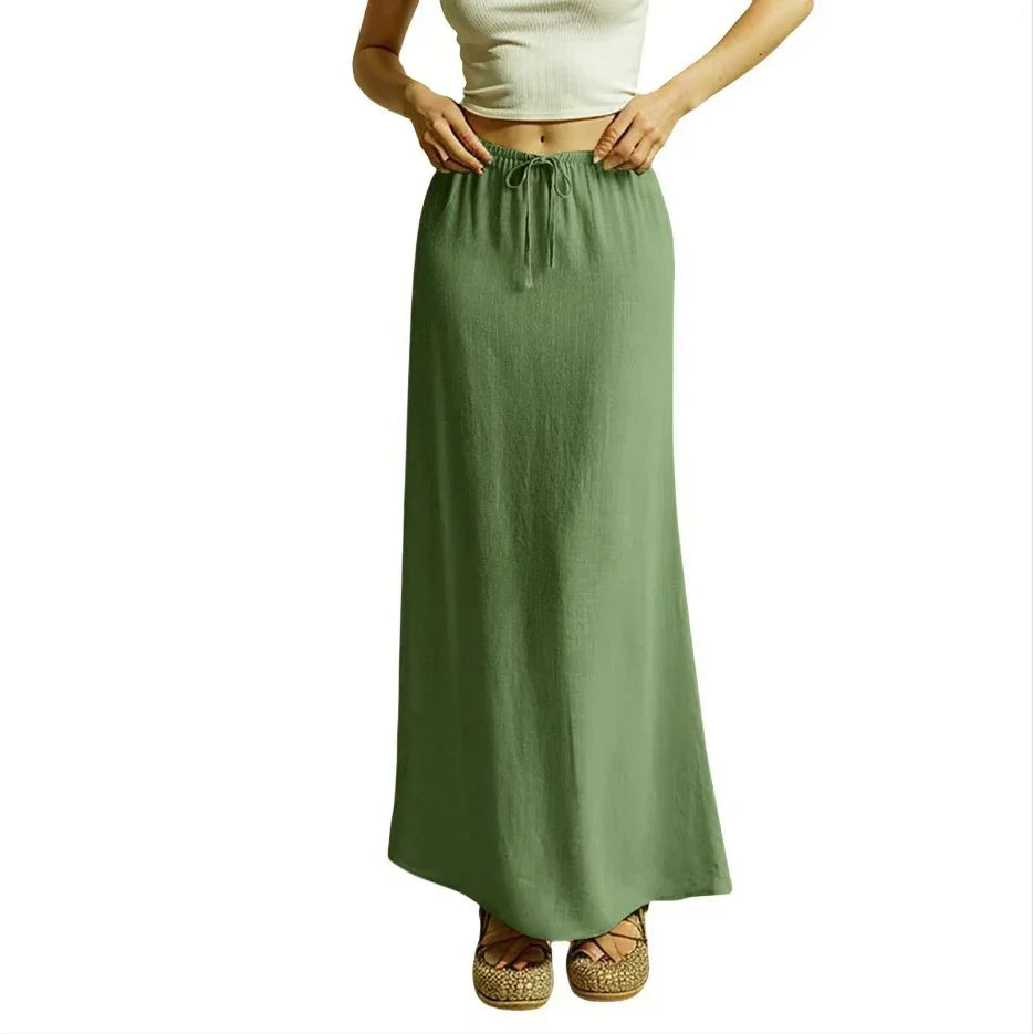 Woman wearing a long casual green drawstring skirt paired with woven platform sandals and a white crop top