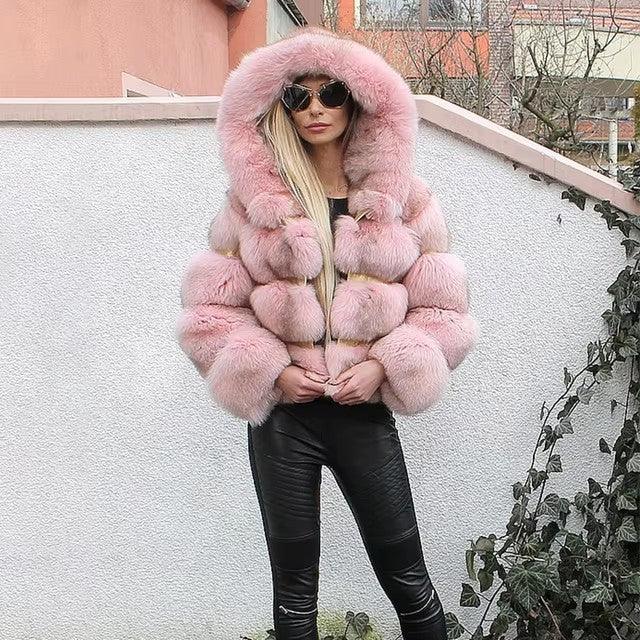 Woman wearing a luxurious pink fur coat with hood and black sunglasses, paired with black leather pants