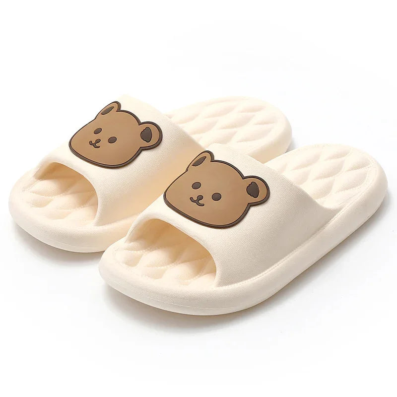 Cream-colored slide slippers with quilted soles and cute brown bear face designs on the straps