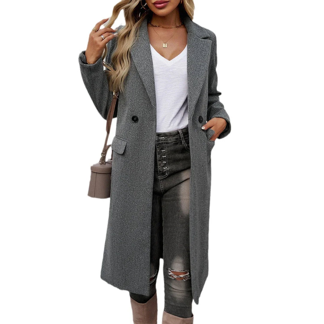 Woman wearing a long grey double-breasted wool coat over white V-neck top and distressed black jeans