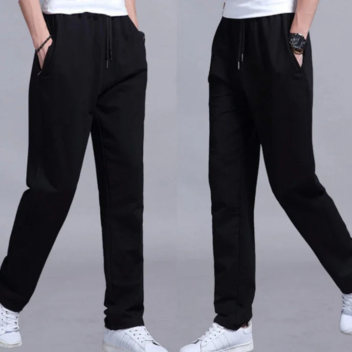Men's black casual drawstring pants paired with white sneakers, shown in two poses