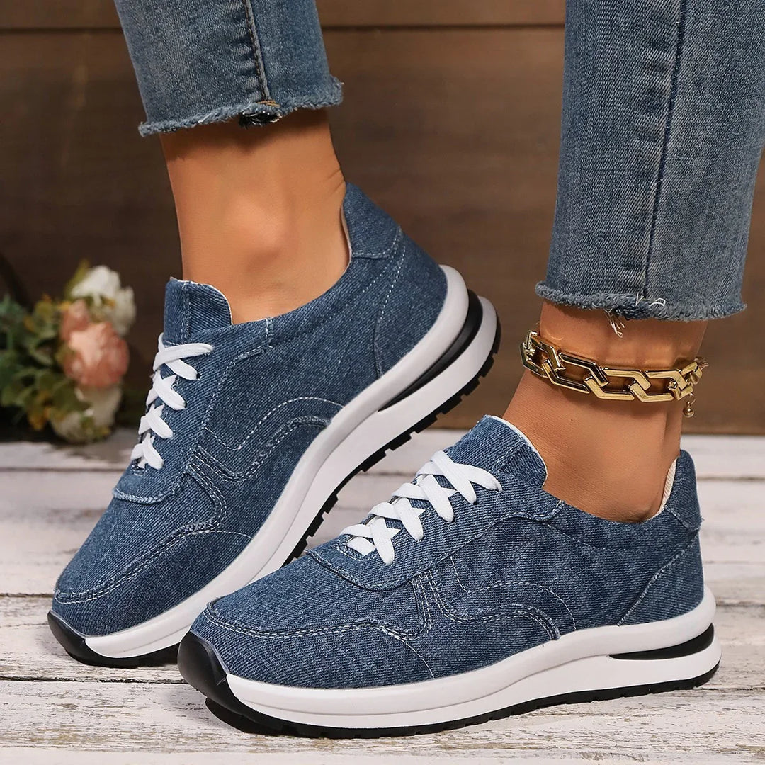 Blue denim casual sneakers with white laces and black and white sole worn with frayed hem jeans and gold chain anklet