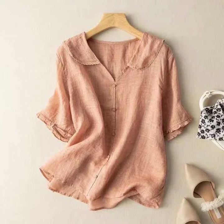 Light pink linen blouse with scalloped collar and button front, paired with beige pointed flats and floral bag