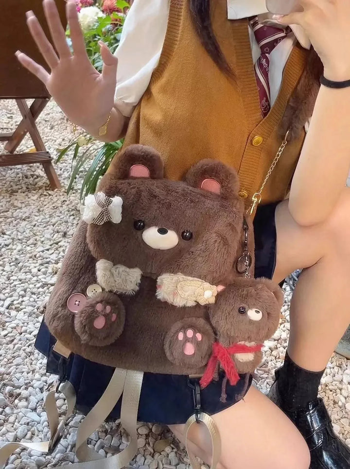 Person wearing brown vest with teddy bear plush backpack and keychain, sitting on gravel outdoors