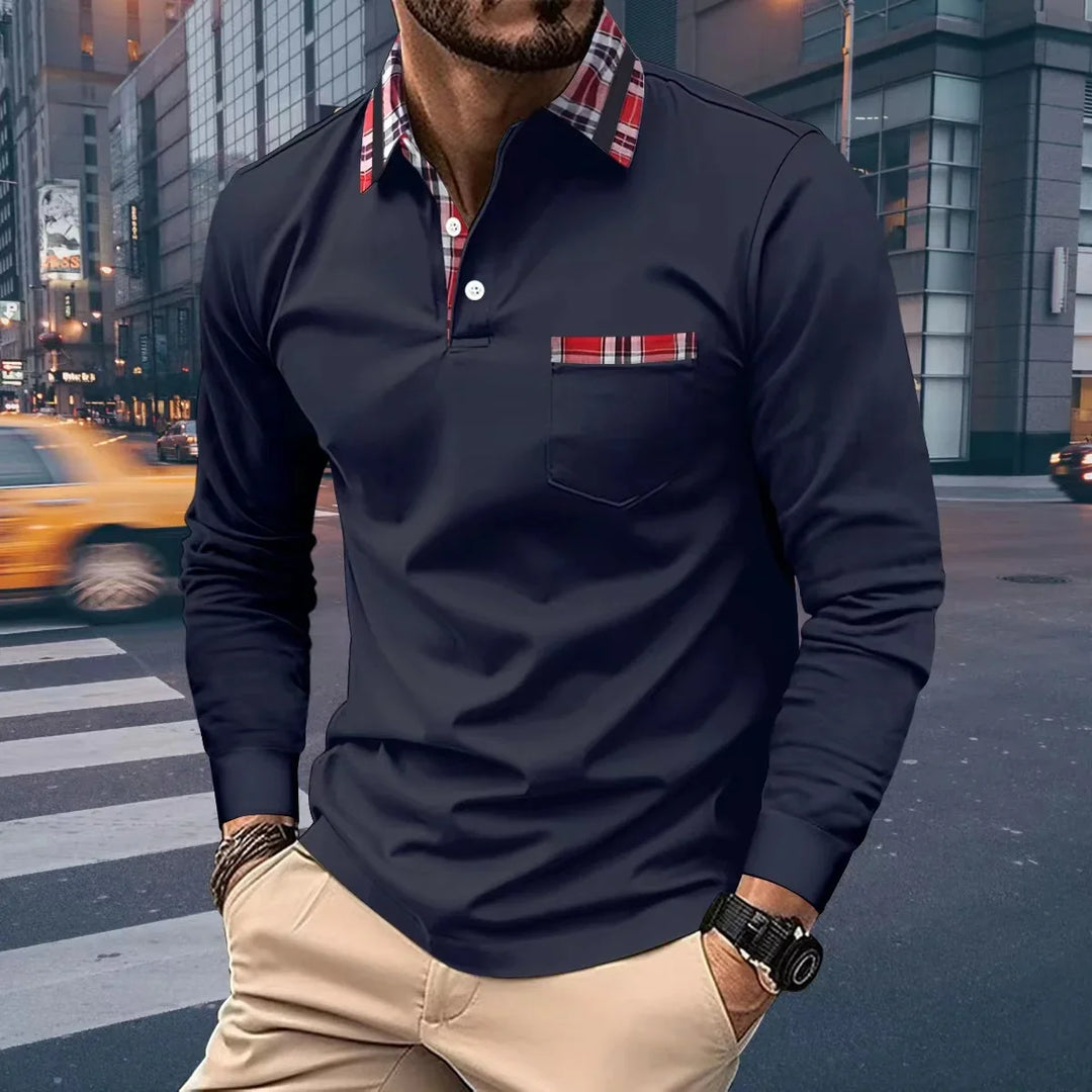 Man wearing navy long-sleeve polo shirt with red plaid collar and pocket detail in urban street setting