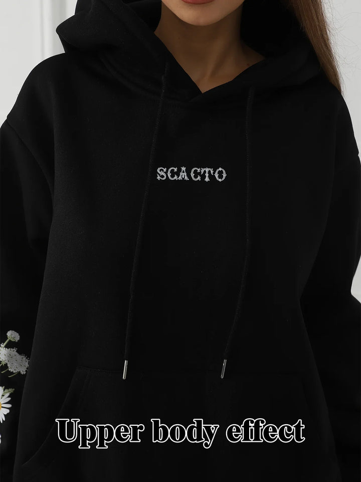 Close-up of a person wearing a black hoodie with white stylized text 'SGACTO' on chest and a front pouch pocket