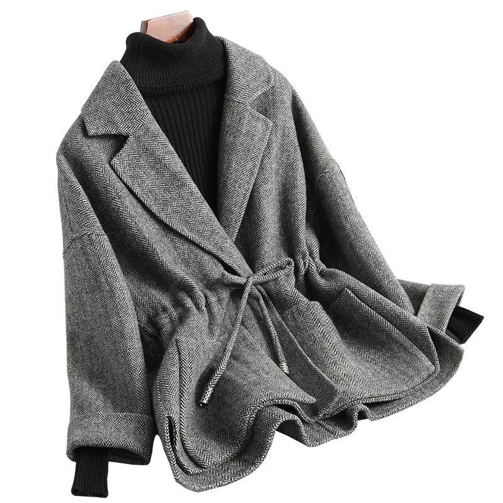 Gray herringbone belted jacket with wide lapels over black ribbed turtleneck sweater