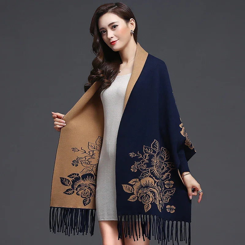 Woman wearing reversible navy and camel floral shawl with fringe over light gray dress on gray background