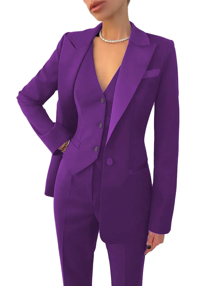 Woman wearing a tailored purple pantsuit with blazer and vest, accessorized with pearl necklace