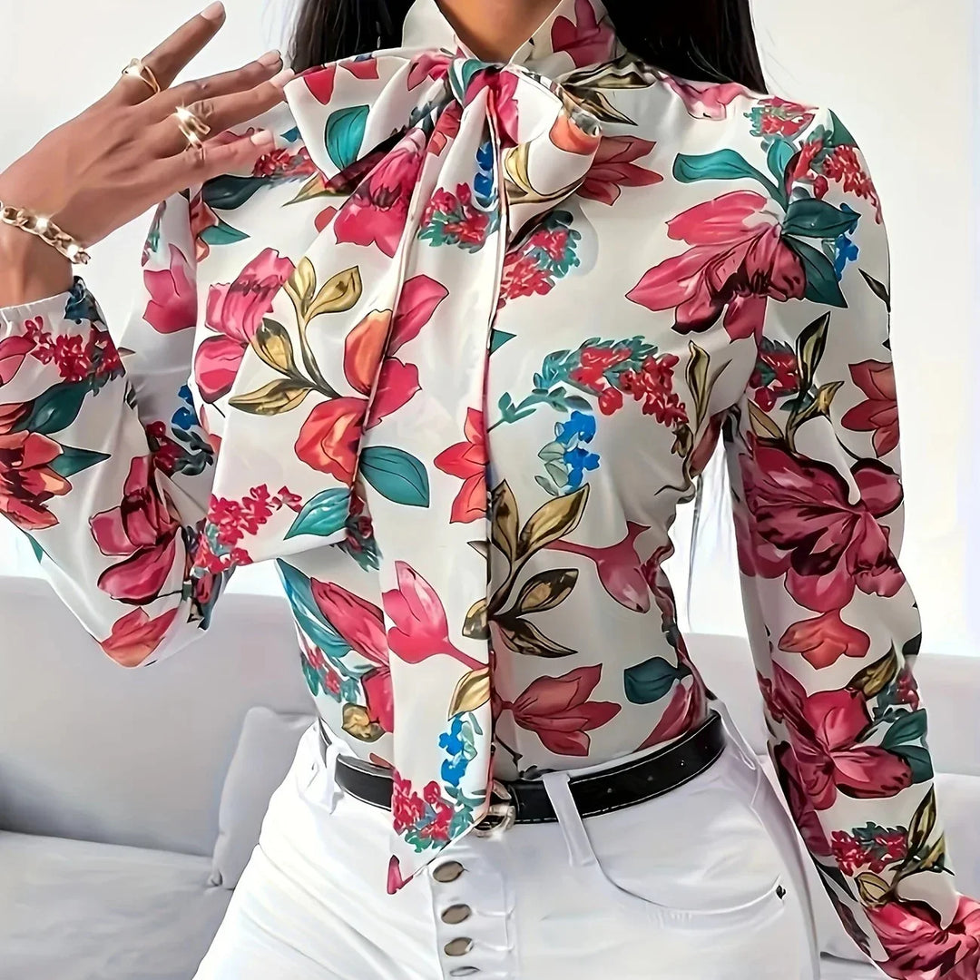 Woman wearing a floral print blouse with a large bow tie and white high-waisted pants