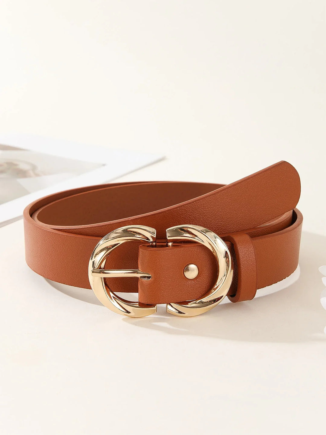 Brown leather belt with gold double rounded buckle on white surface