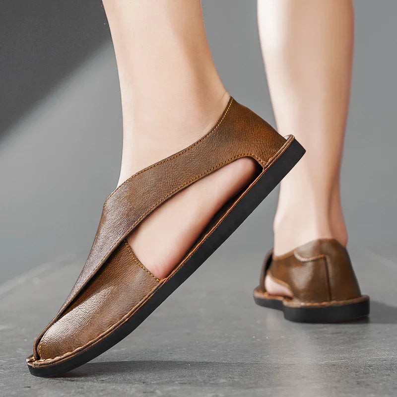 brown leather slip-on sandals with cutout design on feet on gray floor