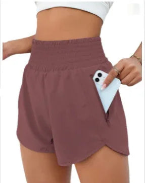 Close-up of woman wearing mauve high-waisted shorts with side pocket holding a smartphone