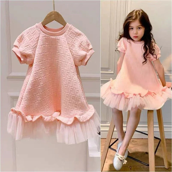 Pink quilted baby dress with short puff sleeves and tulle hem, displayed on hanger and worn by child