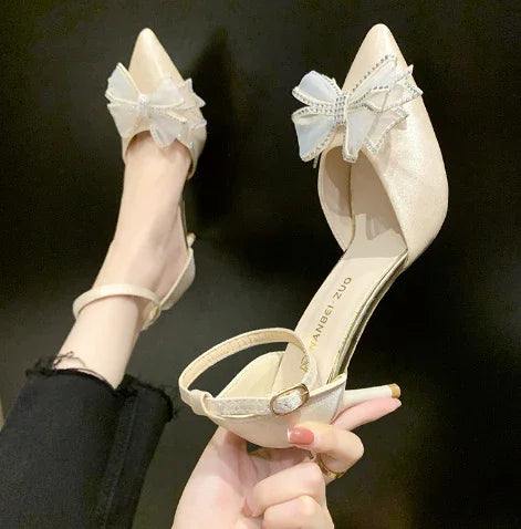 Elegant pearl white high heel shoes with large decorative bows and ankle straps