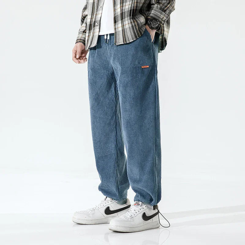 Man wearing blue corduroy pants with elastic cuffs and white Nike sneakers in casual outfit
