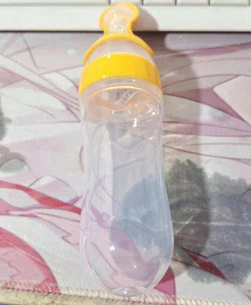 clear baby food feeder with yellow cap and silicone nipple on patterned cloth background