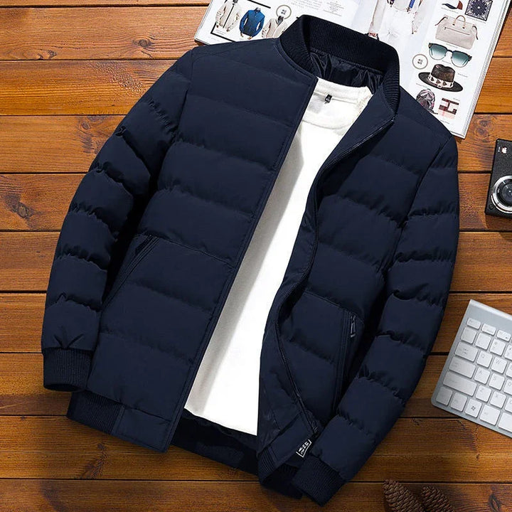 Navy blue padded winter jacket with black ribbed collar and cuffs over white shirt on wooden surface