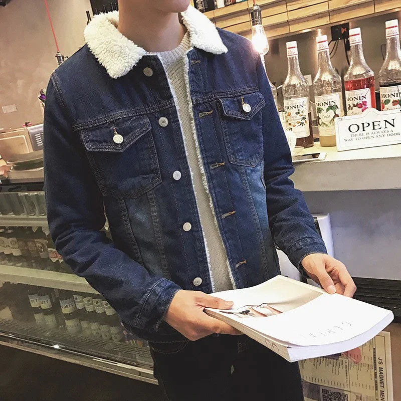 Man wearing blue denim jacket with white sherpa collar holding magazine in a cafe setting
