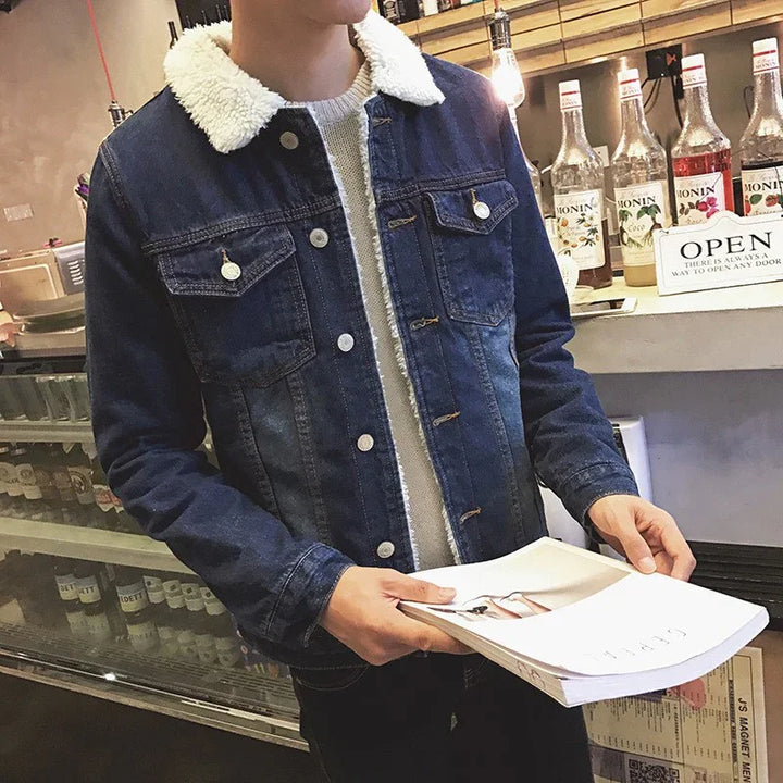 Man wearing blue denim jacket with white sherpa collar holding magazine in a cafe setting