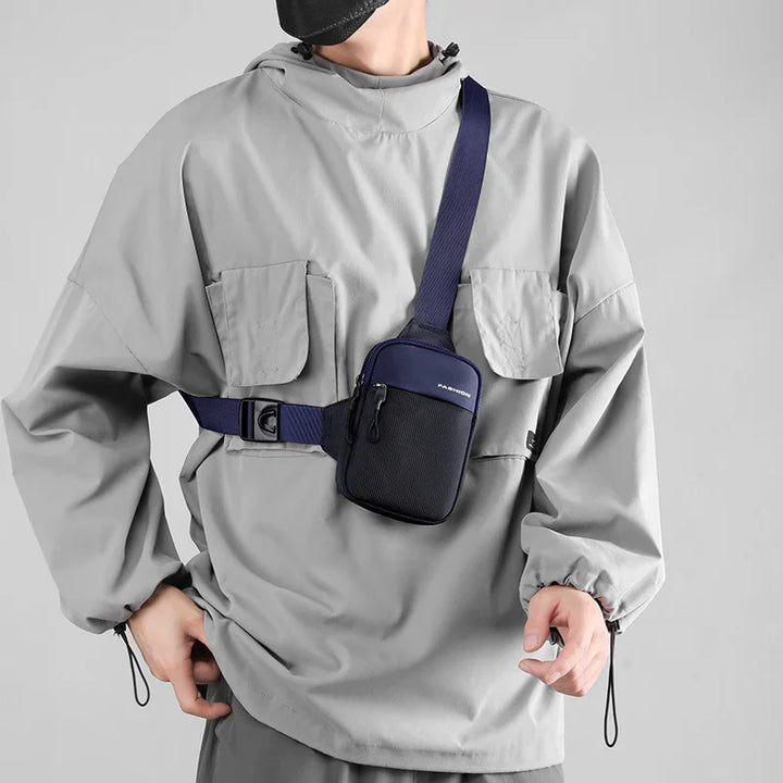Man wearing light gray oversized jacket and black face mask with navy blue crossbody sling bag