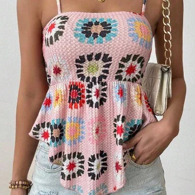 Woman wearing a pink textured smocked tank top with colorful floral patterns and light denim shorts