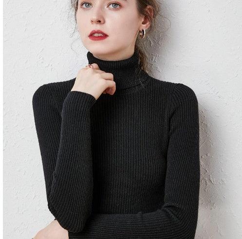 Woman wearing a black ribbed turtleneck sweater posing against a white textured wall