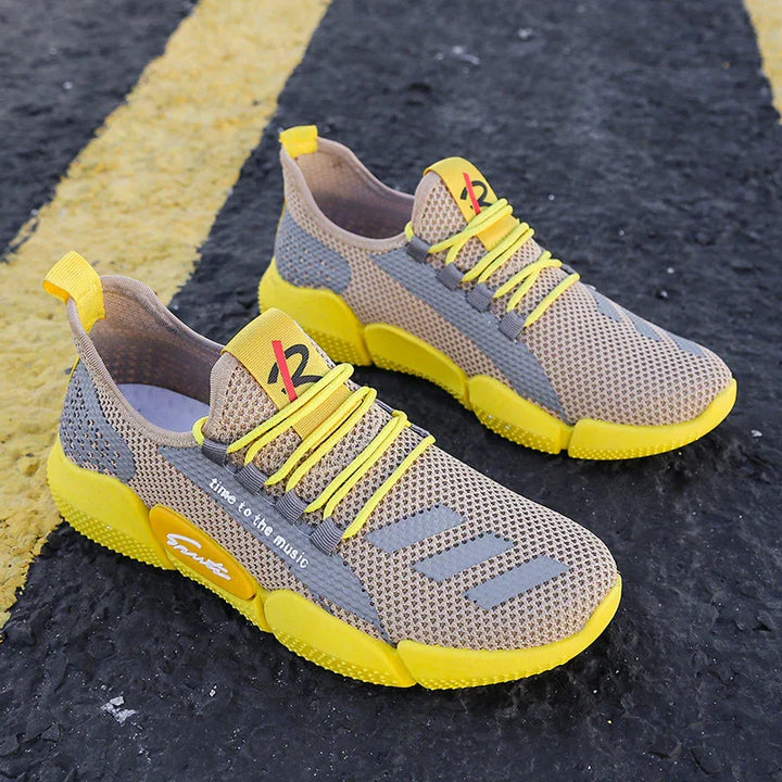 Beige and yellow breathable mesh sneakers with bright yellow soles and laces on asphalt with yellow lines