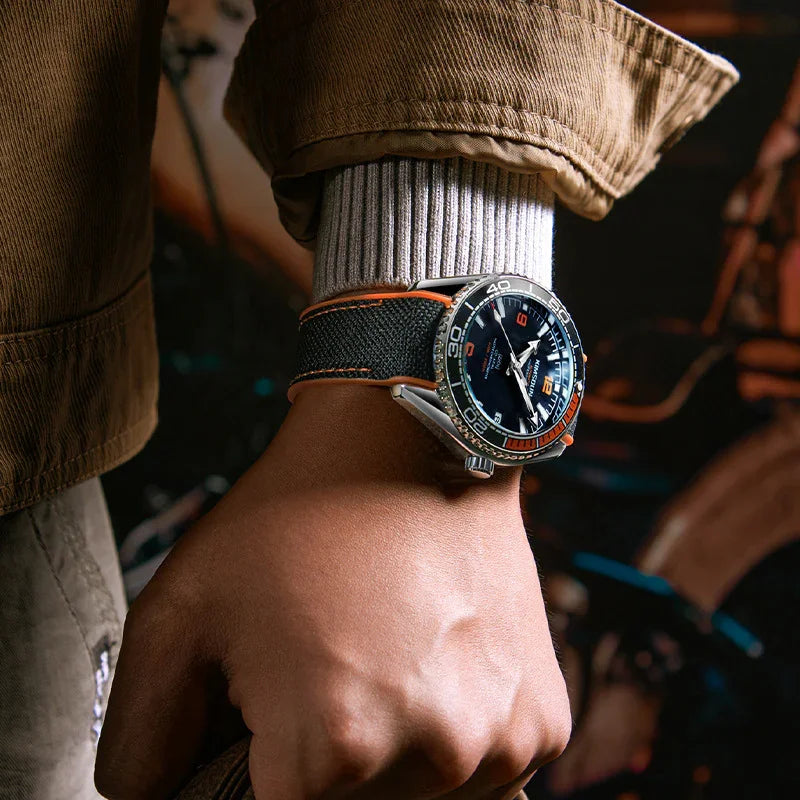 Close-up of wrist wearing luxury diver watch with black and orange bezel and fabric strap