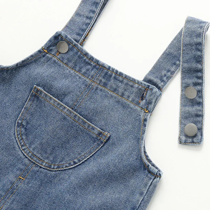 Close-up of blue denim overall straps with metal buttons and front pocket stitching
