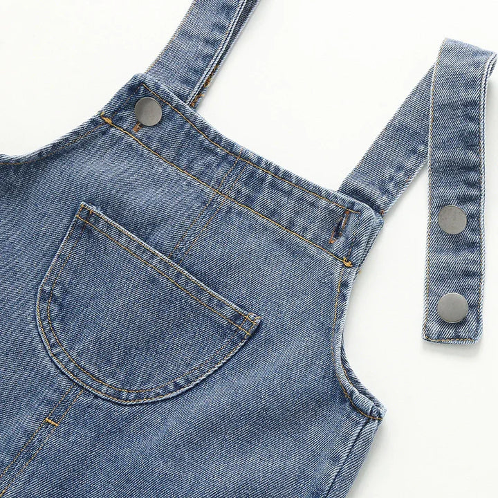 Close-up of blue denim overall straps with metal buttons and front pocket stitching