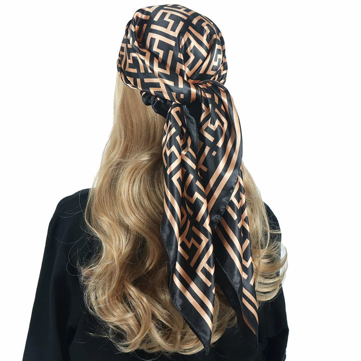 Woman with long blonde hair wearing black and gold patterned silk head scarf tied at back