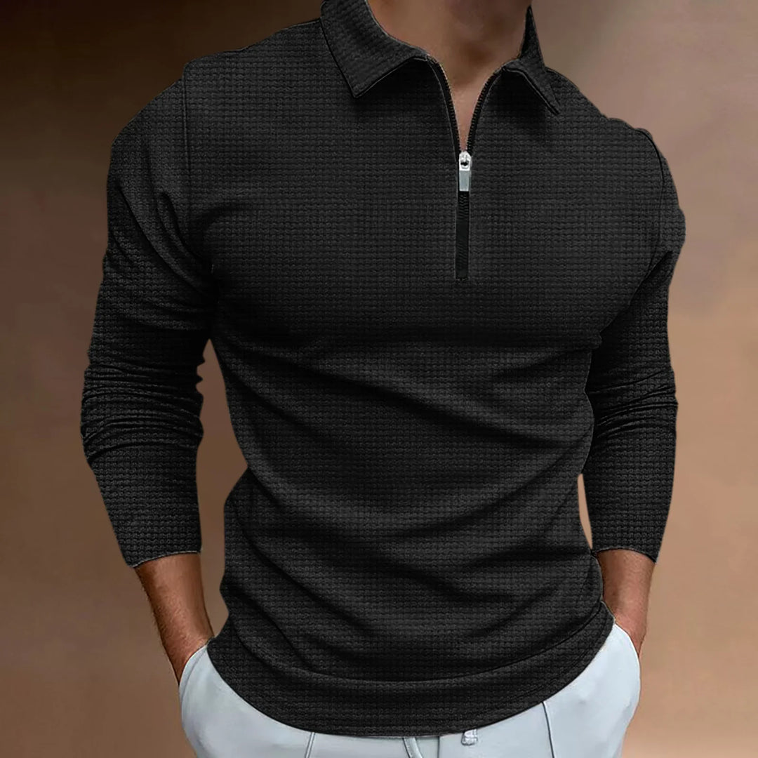 Man wearing black textured long-sleeve polo shirt with front zipper and white pants