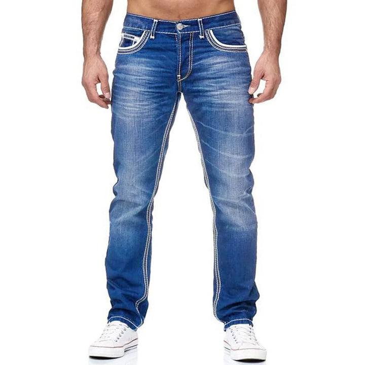 Front view of man wearing slim fit blue denim jeans with white stitching and white sneakers