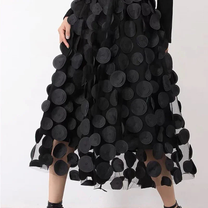 Woman wearing a black midi skirt adorned with large textured black circular appliques on sheer fabric