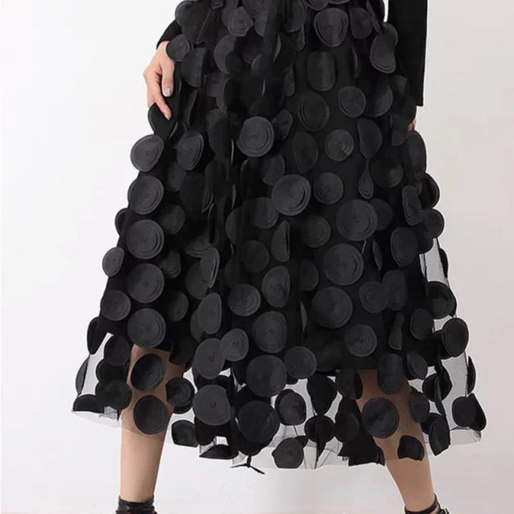 Woman wearing a black midi skirt adorned with large textured black circular appliques on sheer fabric