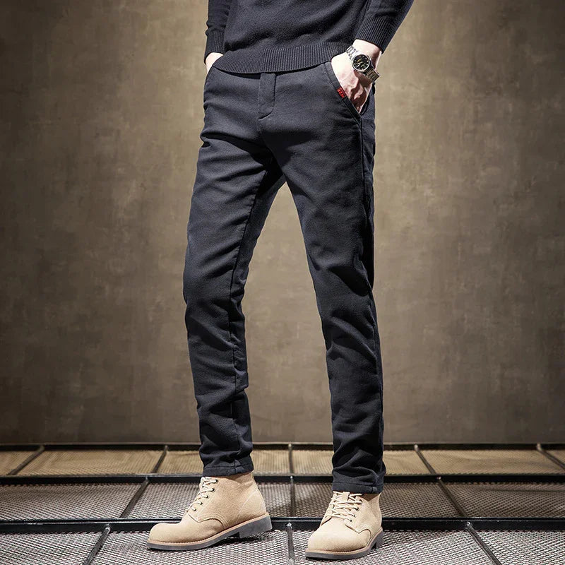 Man wearing slim black pants and beige suede lace-up boots on metal grid floor