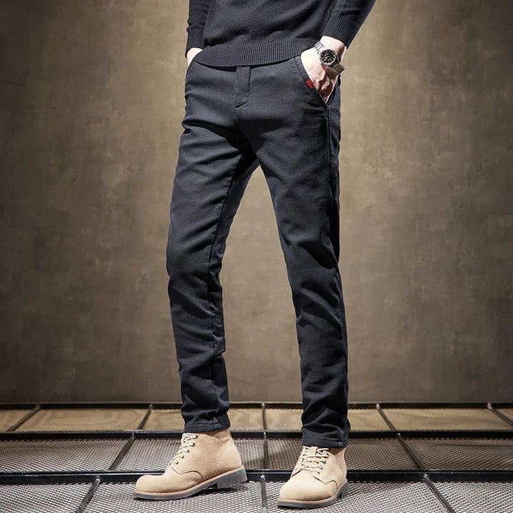 Man wearing slim black pants and beige suede lace-up boots on metal grid floor