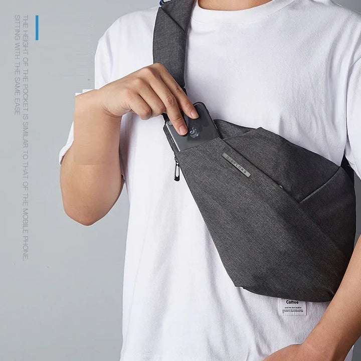 Person wearing white shirt placing smartphone into gray crossbody sling bag pocket