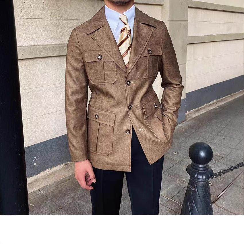 Man wearing brown tailored blazer with patch pockets and striped tie, standing on urban sidewalk