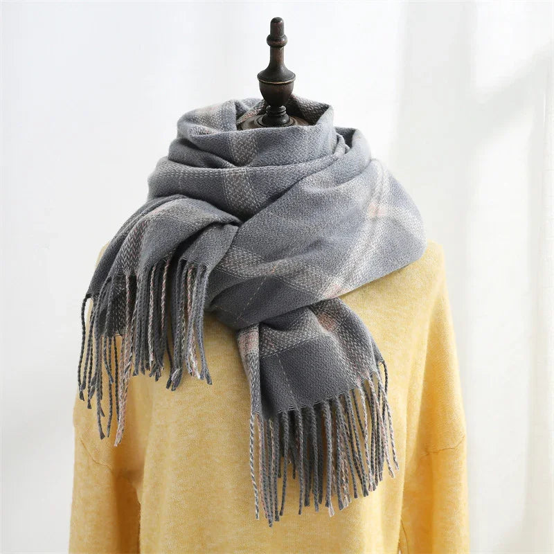 Cozy gray fringed plaid scarf wrapped around mannequin dressed in yellow sweater