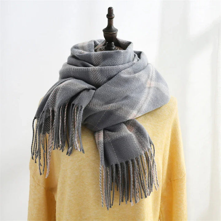 Cozy gray fringed plaid scarf wrapped around mannequin dressed in yellow sweater