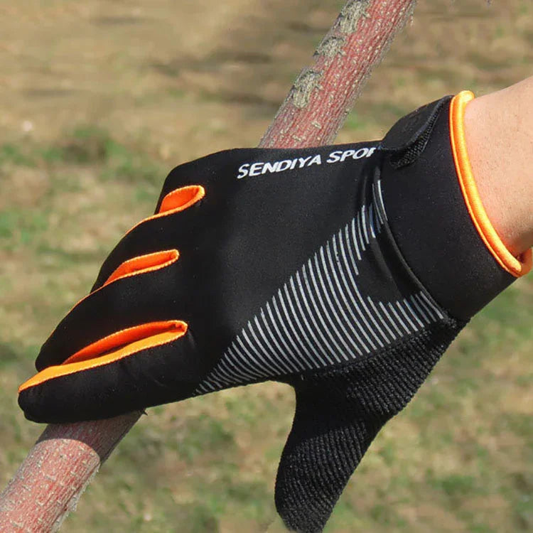Black and orange Sendiya Sport gloves gripping a tree branch outdoors on a sunny day