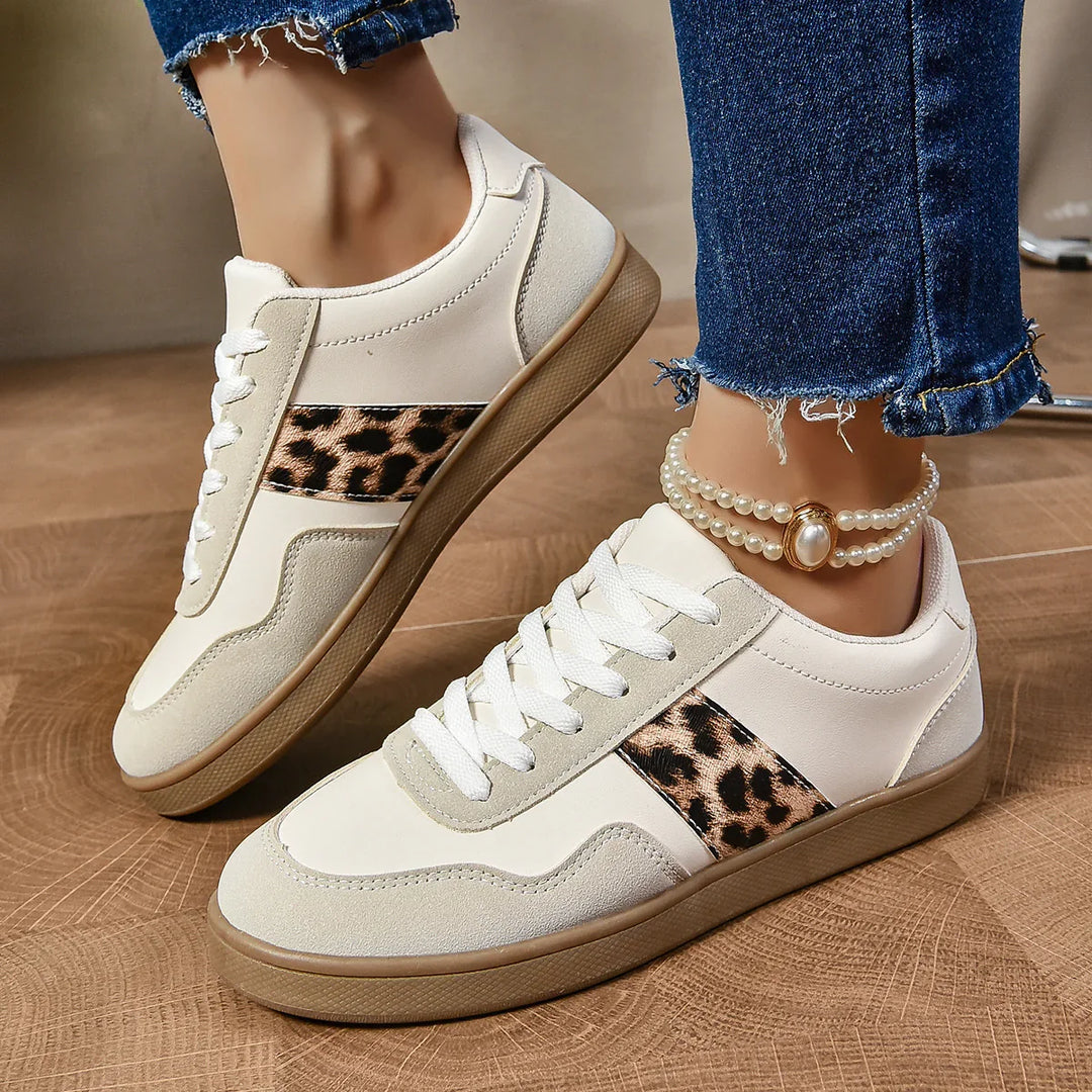 White casual sneakers with leopard print side accents and gum soles worn with blue frayed jeans and pearl anklet
