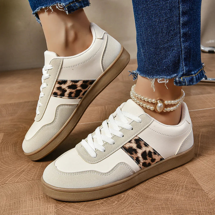 White casual sneakers with leopard print side accents and gum soles worn with blue frayed jeans and pearl anklet