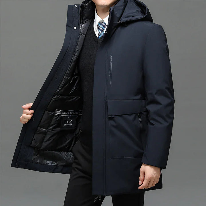 Man wearing navy blue insulated winter coat with hood, black sweater, and blue striped tie