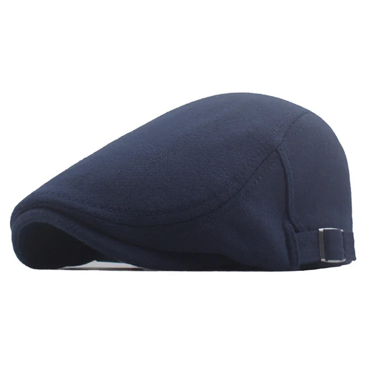 Navy blue flat cap with adjustable side strap, classic men's casual hat on white background